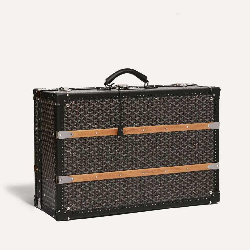 Authentic Goyard travel trunks — Goyardine canvas rigid travel trunk in tan-on-natural colorway with brass locks and leather corner guards, from the verified Goyard range at The Authentic Bags